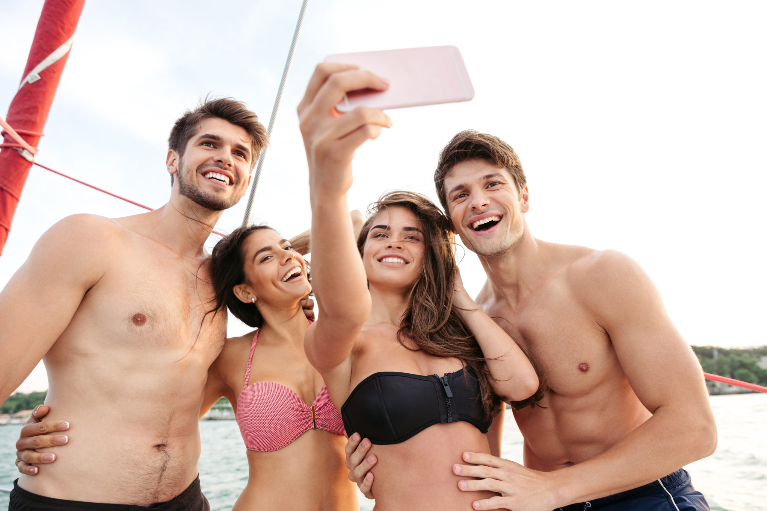 Smiling happy friends standing on yacht deck and making selfie